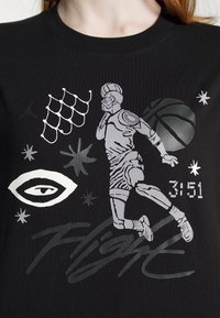 Black T-shirt featuring a stylized silver graphic of a basketball player, stars, an eye, and the text "Flight" with a numeric detail.