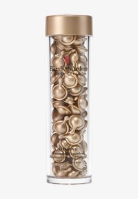 Transparent cylindrisk behållare fylld med gyllene, tårformade serumkapslar, märkta "Vitamin C Ceramidkapslar." Gyllene lock på toppen.