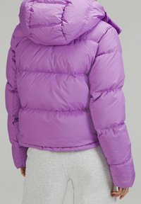 Doudoune violette avec un design matelassé, dotée d'une capuche, de poignets élastiques et d'un ourlet resserré. Matière en nylon mat avec une texture lisse.