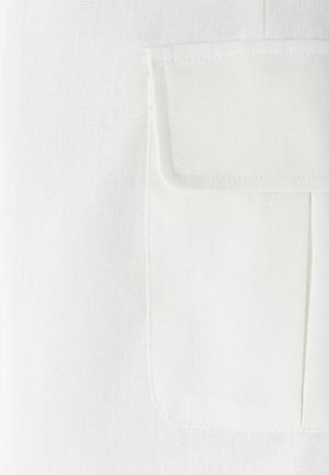 Tejido blanco con un tejido texturizado, que presenta un bolsillo cuadrado en el lado izquierdo, bordes bien cosidos y líneas horizontales sutiles.