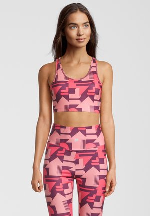 Sostén deportivo rosa y leggings con patrones geométricos en diferentes tonos de rosa, púrpura y rojo. Hechos de un material suave y elástico.