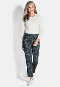 Witte lange mouwen top gecombineerd met gemêleerde donkerblauwe broek met groene, bruine en lichtblauwe krullen. Gedragen met witte sneakers.