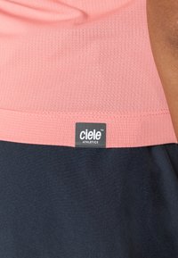 Roza in mornarsko modra športna majica brez rokavov, ki ima teksturirano površino, kontrastne barve in vidno oznako "ciele ATHLETICS".