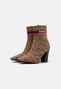 Bottes de cheville en maille à motif marron avec un bout pointu, un talon bloc noir, et une bande logo en bordeaux et rose autour du haut.