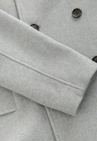 Grijs visgraatcoatstof met een gladde textuur, voorzien van donkere knopen en een opgerold mouwdetail.