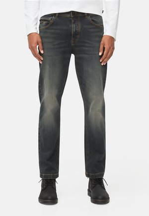 Dunkelblaue Jeans aus Denim mit verblassten Akzenten, gerades Bein-Design, fünf Taschen und kontrastierenden Nähten. Kombiniert mit schwarzen Schnürstiefeln.