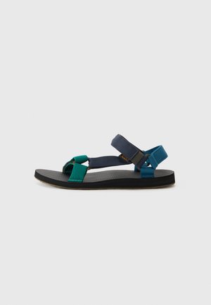 Sandal de colores con tiras de textil en verde y azul, suela negra texturizada y cierres ajustables para un ajuste seguro.