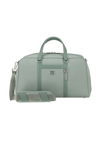 Erweiterbare Reisetasche aus weichem mintgrünem Stoff, mit zwei oberen Griffen, einem abnehmbaren Schultergurt und einem Logo-Patch auf der Vorderseite. Silbernene Akzente.