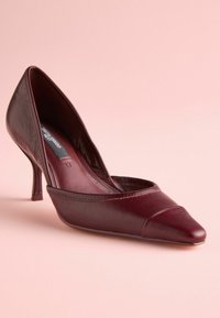 Pumps in pelle bordeaux con tacco alto e punta affusolata, caratterizzate da una finitura liscia e un design curvo; tacco stiletto basso.