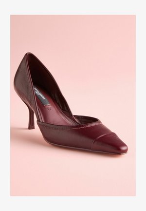 Pantofi cu toc înalt din piele bordeaux, cu vârful ascuțit, având un finisaj neted și un design curbat; un toc stiletto mic.