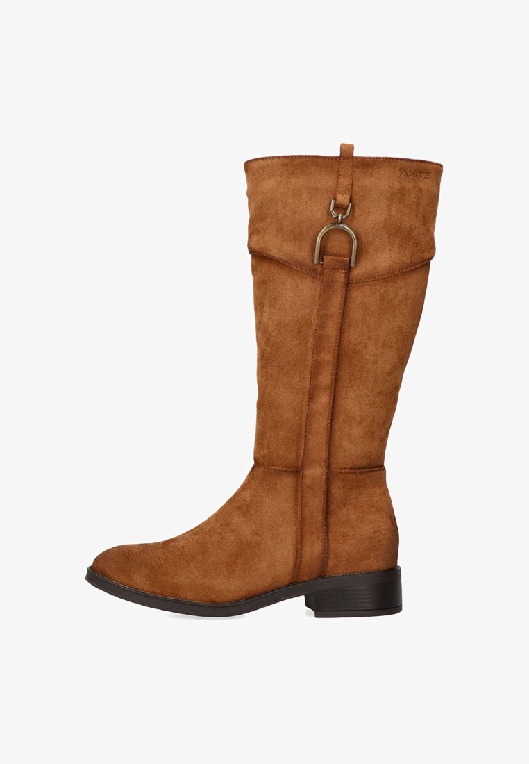 Bota marrón de ante hasta la rodilla con punta redondeada, suela plana y un detalle metálico decorativo en la parte superior. Textura suave con detalles de costura.