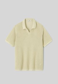 Polo en maille beige à manches courtes avec motif ajouré, col, poignets et patte de boutonnage en V côtelés, posé à plat sur fond gris.