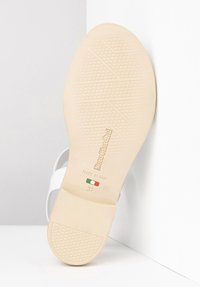 Sandale blanche avec une semelle beige texturée, présentant un logo en relief et une taille 37. Fabriquée en Italie avec un design minimaliste.
