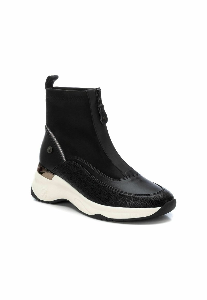 Bottines noires mettant en valeur un mélange de cuir lisse et texturé, une fermeture éclair, et une épaisse semelle blanche avec un accent métallique.