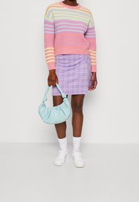 Pull en maille rayé pastel, mini-jupe à carreaux lavande, sac à épaule bleu clair, baskets blanches et chaussettes montantes.