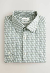 Złożona, koszula z długim rękawem na guziki, z geometrycznym wzorem tkanym w białym, szarym i ciemnozielonym kolorze, z ostrokątnym kołnierzykiem i guzikami z przodu.
