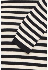 Randig stickad tröja med växlande svarta och krämfärgade horisontella ränder, med en ribbad svart mudd och en mjuk, elastisk textur.