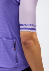 Μωβ ποδηλατική φανέλα με φερμουάρ στην τσέπη στο πίσω μέρος και μωβ μανίκι με δύο μωβ ρίγες και κείμενο "CASTELLI".