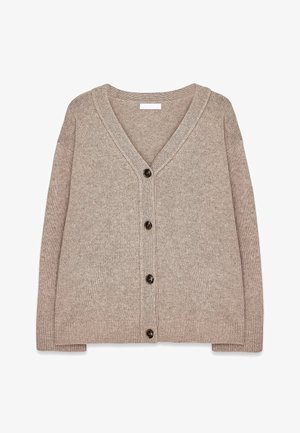 Bežinis megztinis su V formos iškirpte, su rausvomis kraštinėmis ir penkiais rudiems mygtukais per priekį. Minkšta tekstūra ir laisvas fasonas.