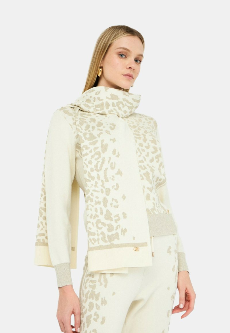 Maglione color crema con un motivo a stampa leopardata testurizzato in beige chiaro. Presenta un colletto alto, maniche ampie e dettagli a coste.