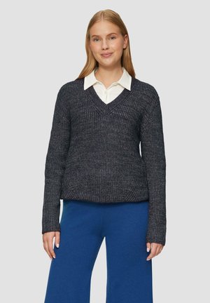 Donkerblauwe gebreide trui met een v-hals, ribbelstructuur en lange mouwen, gecombineerd met een wit overhemd met kraag eronder.