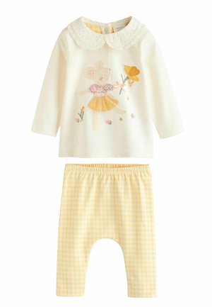 Kremfarvet bluse med lange ærmer, blondekrave og broderet bjørnemotiv, kombineret med gule gingham leggings. Blødt bomuldsstof overalt.