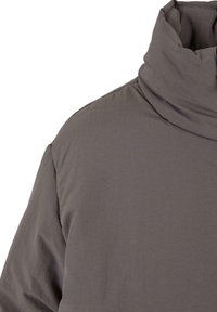 Grå, myk stoffkrage med høy krage, som har en jevn tekstur og minimale sømmer. Designet fokuserer på varme og komfort.