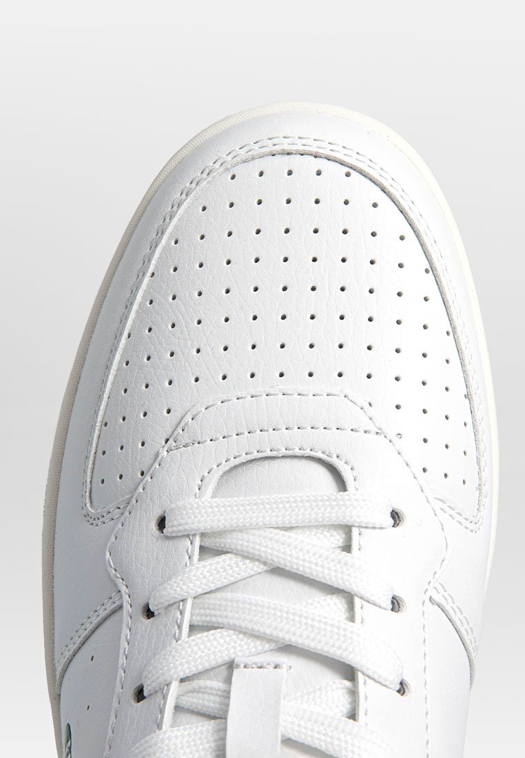 Witte leren sneaker met geperforeerde neuskap, ronde vorm, gewatteerde rand en platte veters. Gladde textuur met subtiele stikselaccenten.