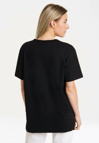 Black cotton t-shirt featuring a relaxed fit, short sleeves, and a round neckline. Smooth texture with no visible patterns or accents.