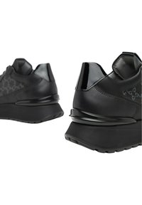 Sneaker sportive nere con tomaia in pelle, dettagli lucidi, pannelli texturizzati e una forma slanciata con suola in gomma spessa.
