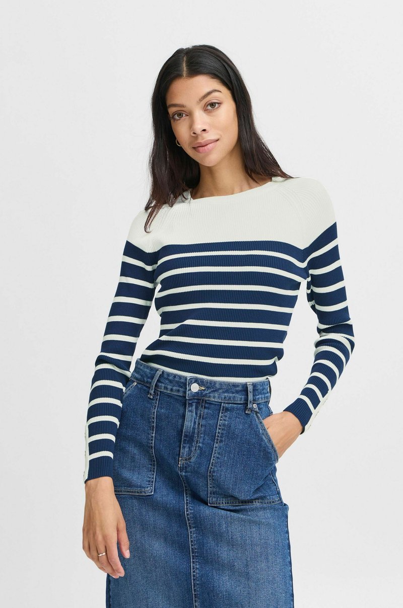 Pull rayé bleu marine et blanc en côtes, à manches longues et encolure ronde, porté avec une jupe en denim taille haute dotée de poches avant.