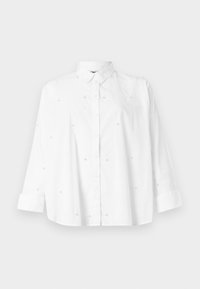 Valge puuvillane särk nööbiga ees, pikkade varrukatega ja helkurilaadsed detailid, mis on ühtlaselt jaotatud kangale. Sile tekstuur.