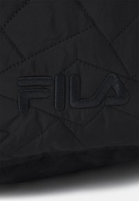Tessuto trapuntato nero con un logo "FILA" ricamato in rilievo. La texture è liscia con una superficie decorata da forme di diamante.