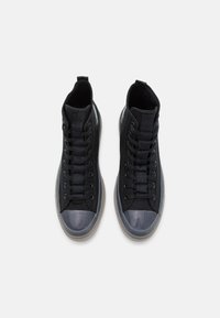 Schwarze High-Top-Sneaker mit einem strukturierten Canvas-Obermaterial, Gummikappe und Schnürdesign. Klarsichtsohle mit kontrastierenden Akzenten.