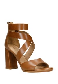 Braune Leder-Absatzsandalen mit einem massiven Blockabsatz. Sie verfügen über überkreuzte Riemen und ein offenes Zehendesign mit einer glatten Textur.