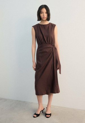 Bruine, knie-lange jurk met een getailleerd lijfje en overslagdetail, voorzien van een brede halslijn en zijdelingse strik. Soepele textuur, mouwloos ontwerp.