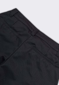 Pantaloni di stoffa nera con una texture liscia, dotati di due tasche posteriori e passanti per cintura. Il tessuto presenta sottili righe verticali.