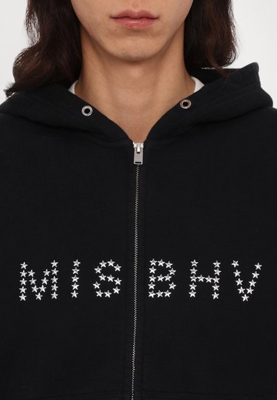 Black zip-up hoodie with a silver star-patterned logo "MISBHV" across the front. Features a drawstring hood and front zipper.