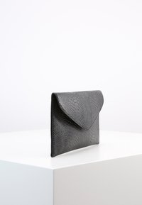 Musta keinonahka käärmeennahkakuosiset clutch-laukku, jossa on kirjekuorimuotoilu, teksturoidulla pinnalla ja kolmiomaisella läppäsuljennalla.