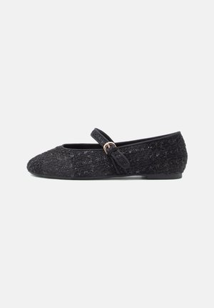 Black ballet flats with a textured fabric upper, square toe, adjustable strap, and a small decorative buckle accent. Flat sole.