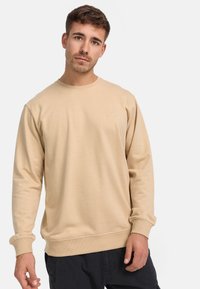 Felpa beige a girocollo realizzata in tessuto morbido, con polsini e orlo a coste. Piccolo logo sulla parte sinistra del petto. Vestibilità comoda.