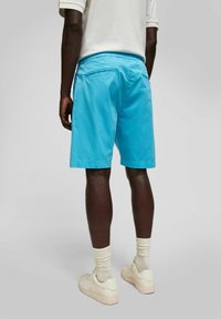 Lichtblauwe shorts van katoen, met een ontspannen pasvorm en twee achterzakken. Gemaakt in combinatie met witte sneakers en crèmekleurige sokken.