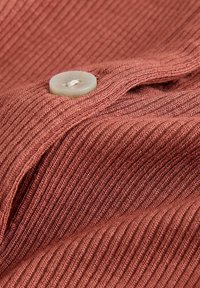 Brown ribbed fabric with a sewn translucent button and thread, showing texture and folds of the material.