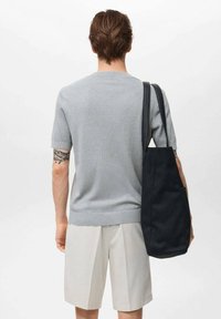 Gray ribbed knit short-sleeve sweater, paired with light beige shorts. A black tote bag is slung over the shoulder, featuring a smooth texture.