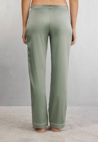 Lichtgroene satijnen pyjamabroek met een ontspannen pasvorm, elastische tailleband en witte bies aan de zoom. Gladde textuur en rechte pijpdesign.