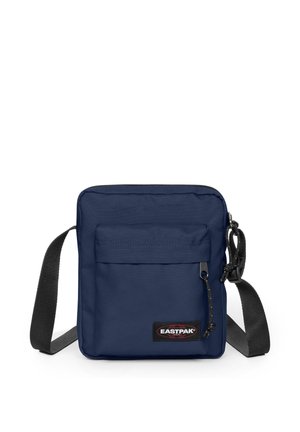 Pieni laivastonsininen olkalaukku etutaskulla, mustalla säädettävällä hihnalla ja Eastpak-logopatchillä alareunassa edessä.