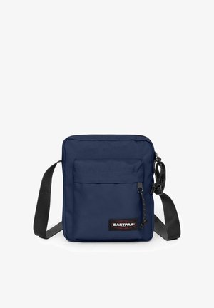 Kleine dunkelblaue Umhängetasche mit Front-Reißverschlusstasche, schwarzem verstellbarem Riemen und Eastpak-Logo-Patch an der unteren Vorderseite.