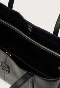 Fekete bőrből készült válltáska texturált felülettel, cipzáras belső zsebbel és logó részlettel a külső részen. Sima pántokkal ellátva.