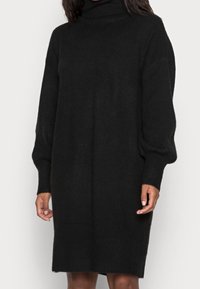 Svart polotröja i klänning modell, tillverkad av mjukt stickat tyg, med långa ärmar, en avslappnad passform och längd till mitten av låret.