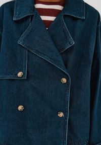 Czarna dżinsowa kurtka dwurzędowa z dużymi klapami, z jasnymi guzikami i delikatnie fakturowaną powierzchnią.